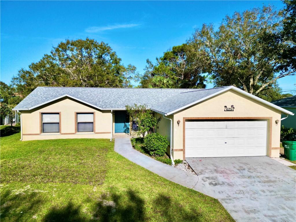 single story home with a garage and a front lawn