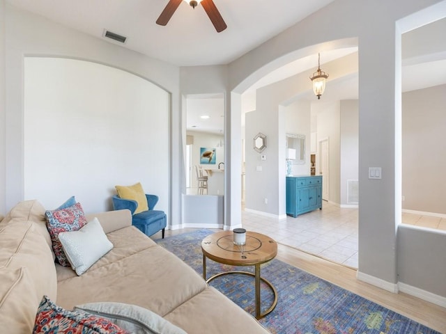 living room featuring ceiling fan, baseboards, visible vents, and light wood-type flooring