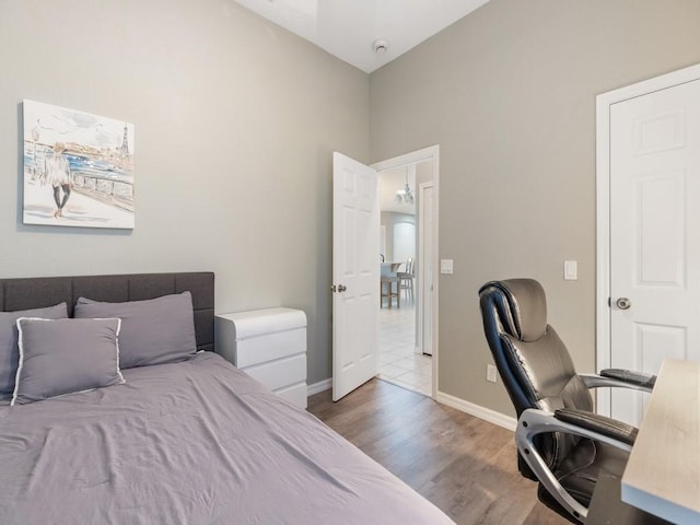 bedroom with vaulted ceiling, wood finished floors, and baseboards