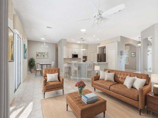 tiled living room featuring ceiling fan with notable chandelier