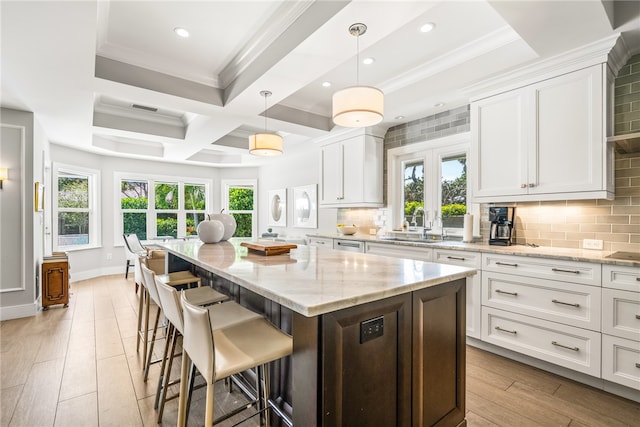 kitchen with a wealth of natural light, white cabinets, hanging light fixtures, and light wood-type flooring