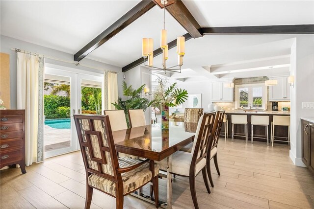 kitchen with wall chimney range hood, hanging light fixtures, light hardwood / wood-style flooring, a kitchen island, and stainless steel appliances