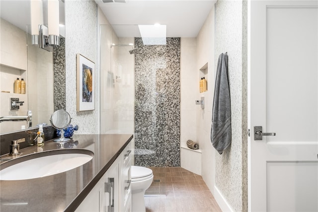 bathroom with tile patterned floors, toilet, vanity, and tiled shower