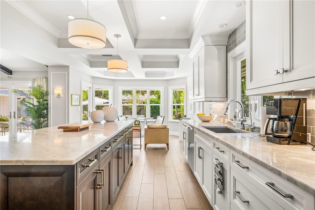 kitchen featuring pendant lighting, light stone counters, white cabinetry, and sink