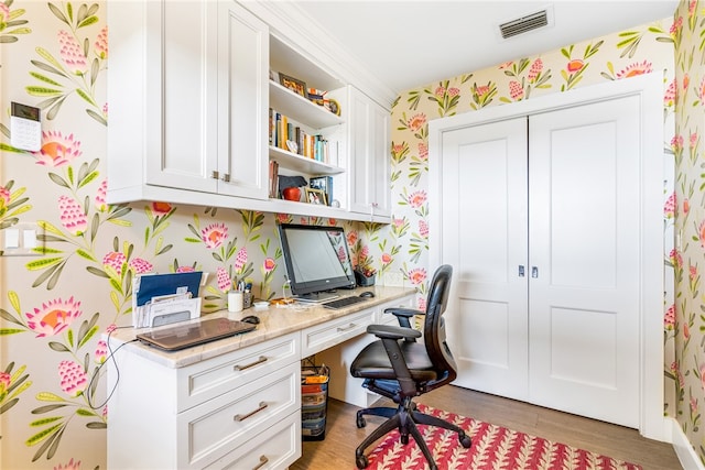 home office featuring light hardwood / wood-style flooring and built in desk