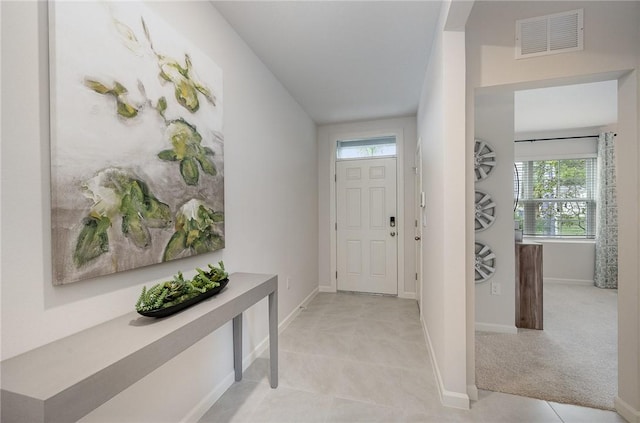 entryway featuring visible vents, light carpet, baseboards, and light tile patterned flooring