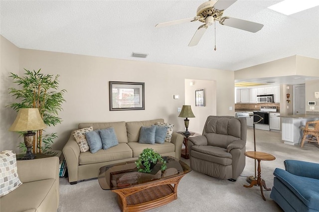 living area with visible vents, ceiling fan, light carpet, and a textured ceiling