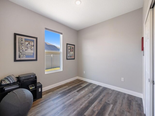 unfurnished office with baseboards and dark wood-style flooring
