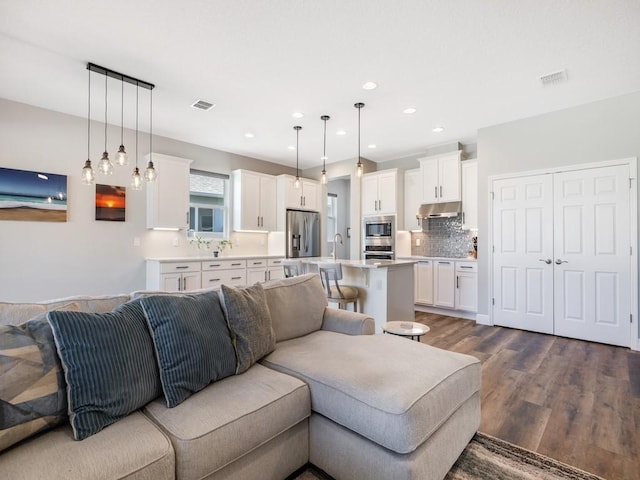 living room with dark wood-style floors, visible vents, and recessed lighting