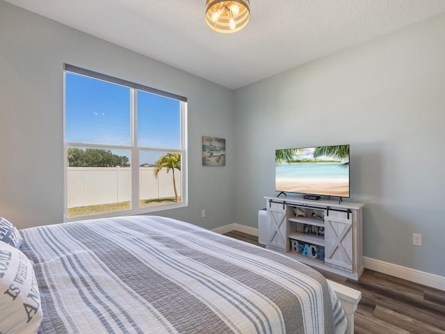 bedroom featuring dark wood finished floors, baseboards, and a textured ceiling