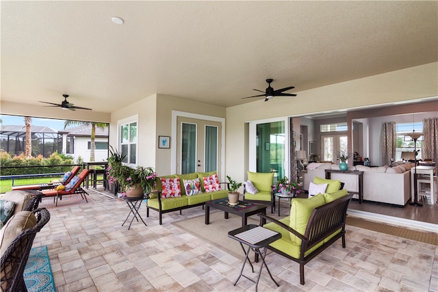 view of patio / terrace with ceiling fan, glass enclosure, and an outdoor living space