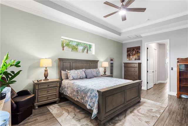 bedroom with dark hardwood / wood-style flooring, a raised ceiling, ceiling fan, and crown molding