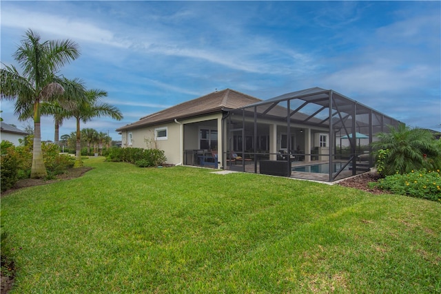 back of house featuring glass enclosure and a yard