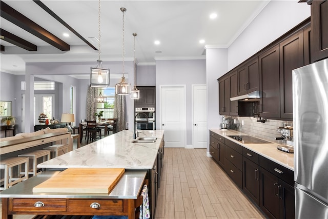 kitchen featuring ornamental molding, beam ceiling, light stone countertops, a spacious island, and appliances with stainless steel finishes