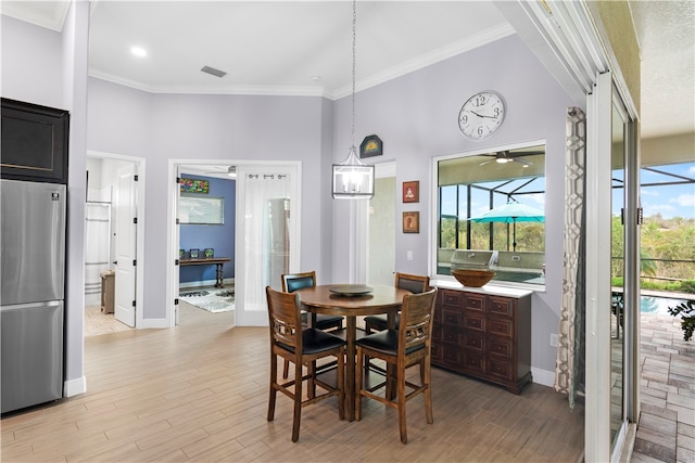 dining room featuring ornamental molding, light wood-type flooring, ceiling fan, and a high ceiling