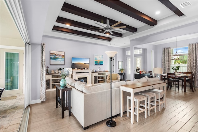 living room with ceiling fan with notable chandelier, beam ceiling, and light wood-type flooring