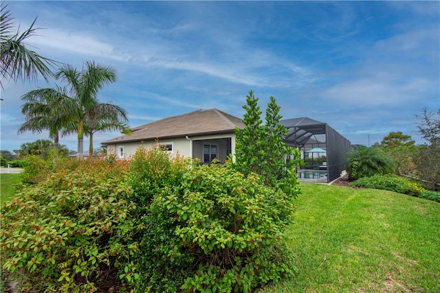 view of side of property with glass enclosure and a yard