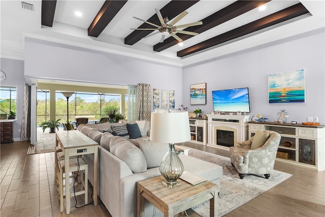 living room featuring a high ceiling, beam ceiling, ceiling fan, and light hardwood / wood-style flooring