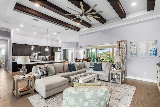 living room featuring ornamental molding, hardwood / wood-style flooring, a high ceiling, beamed ceiling, and ceiling fan