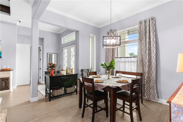 dining area featuring ornamental molding, an inviting chandelier, and light hardwood / wood-style floors