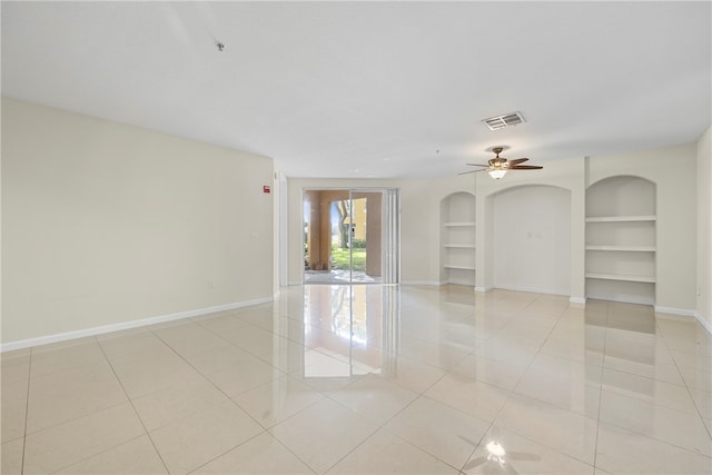 spare room with built in shelves, ceiling fan, and light tile patterned floors