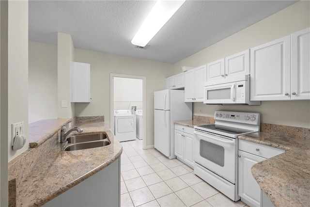 kitchen featuring a textured ceiling, white appliances, sink, washing machine and clothes dryer, and white cabinetry