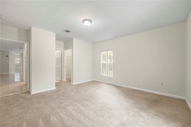 spare room with light carpet and a textured ceiling