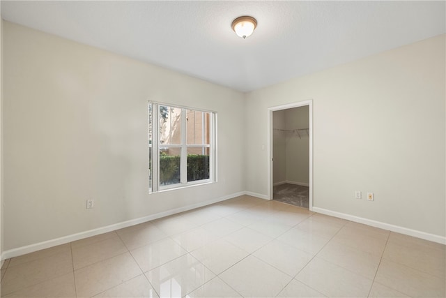 unfurnished bedroom with light tile patterned floors, a walk in closet, and a closet