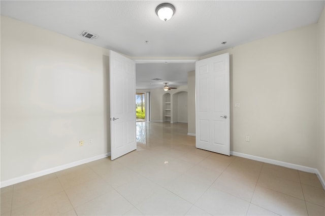 spare room featuring ceiling fan, light tile patterned flooring, and a textured ceiling