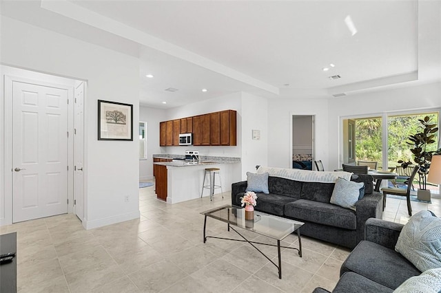 living room with light tile patterned floors and a tray ceiling