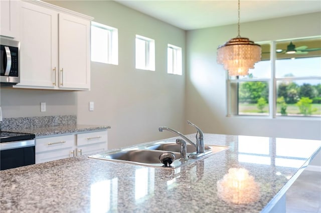 2115 Crowned Eagle Cir SW, Vero Beach, FL 32962 - kitchen featuring stainless steel appliances, white cabinets, and decorative light fixtures