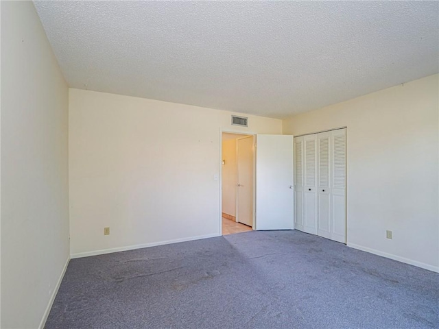unfurnished bedroom featuring a closet, a textured ceiling, visible vents, baseboards, and light colored carpet