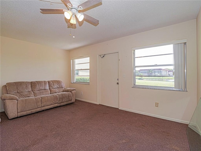 living room featuring carpet, a textured ceiling, baseboards, and ceiling fan