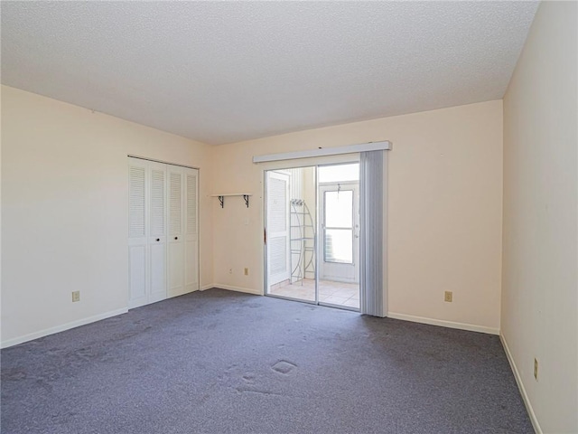carpeted empty room with a textured ceiling and baseboards