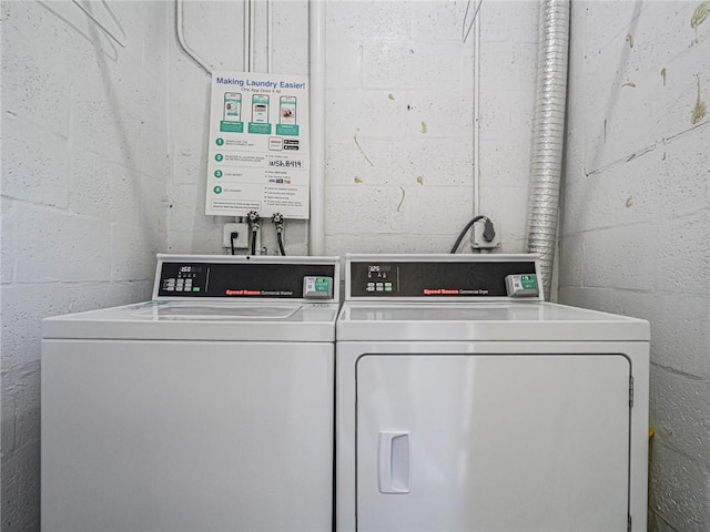 community laundry room with separate washer and dryer and concrete block wall