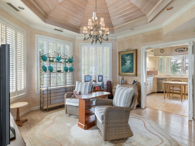 living area featuring ornamental molding, an inviting chandelier, a healthy amount of sunlight, and light hardwood / wood-style flooring