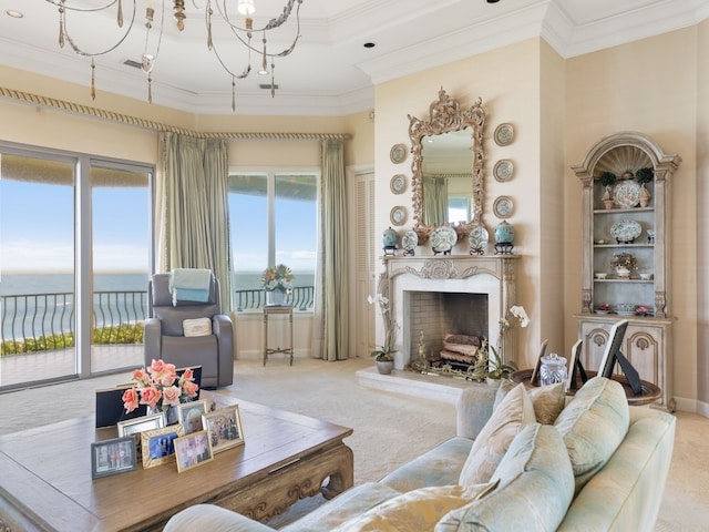 living room with a water view, a premium fireplace, crown molding, a notable chandelier, and light colored carpet