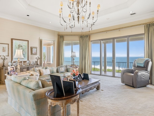 living room featuring ornamental molding, a raised ceiling, a water view, a chandelier, and light colored carpet