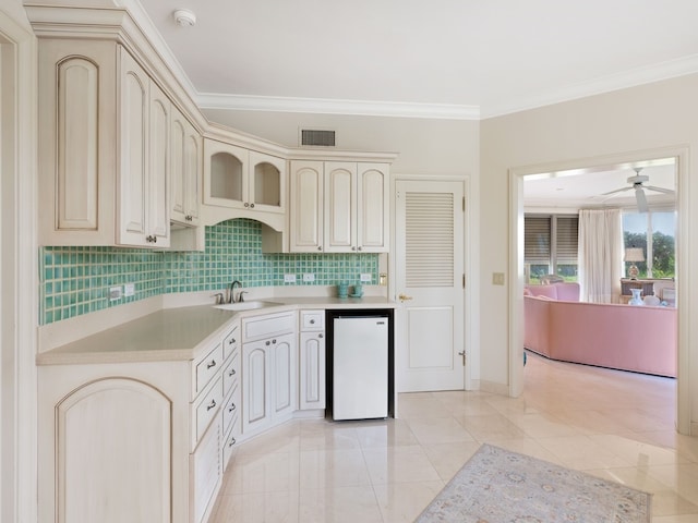 kitchen with sink, cream cabinets, ornamental molding, white dishwasher, and tasteful backsplash