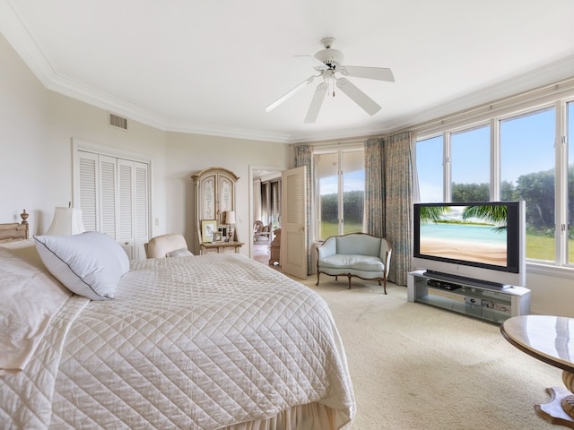 carpeted bedroom with ornamental molding, ceiling fan, and a closet