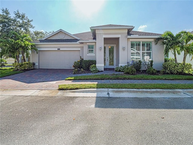 2284 Timberlake Cir, Vero Beach, FL 32966 - view of front of house with decorative driveway, stucco siding, french doors, an attached garage, and roof with shingles