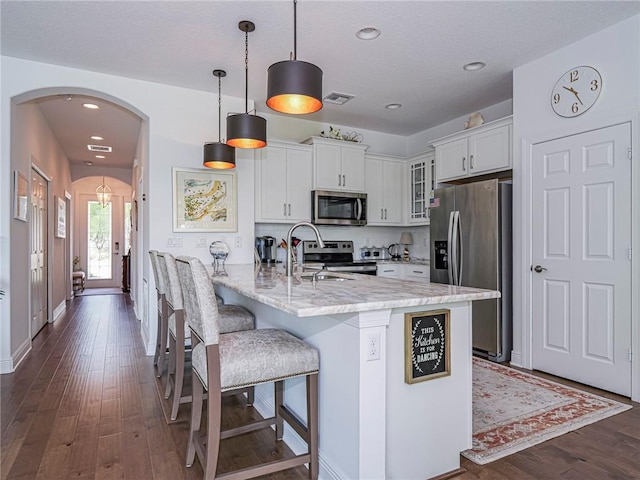 2284 Timberlake Cir, Vero Beach, FL 32966 - kitchen with appliances with stainless steel finishes, arched walkways, glass insert cabinets, dark wood-style floors, and white cabinets