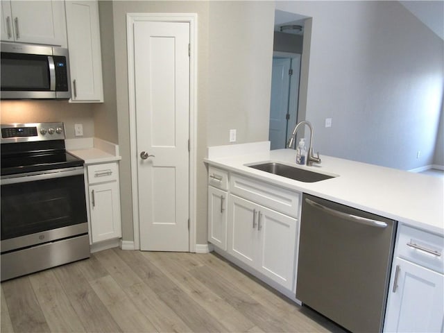 1465 24th Ave SW, Vero Beach, FL 32962 - kitchen featuring appliances with stainless steel finishes, a sink, light wood-style floors, white cabinetry, and light countertops