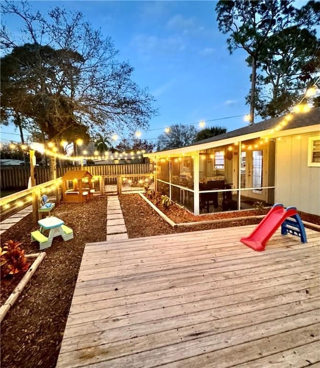 deck at dusk featuring a sunroom