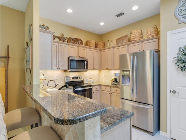7639 15th Ln, Vero Beach, FL 32966 - kitchen featuring appliances with stainless steel finishes, a peninsula, a breakfast bar area, dark stone countertops, and backsplash