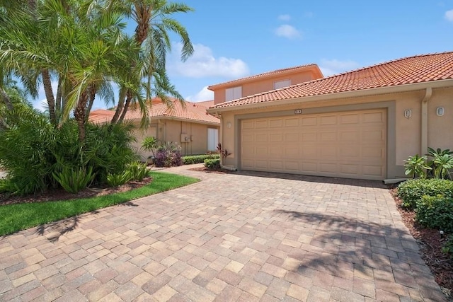 mediterranean / spanish-style home featuring stucco siding, a garage, decorative driveway, and a tile roof