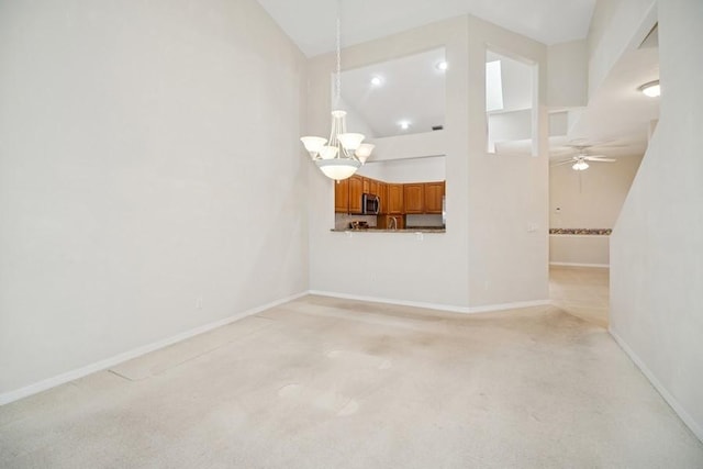 unfurnished living room featuring high vaulted ceiling, a chandelier, light carpet, and a ceiling fan