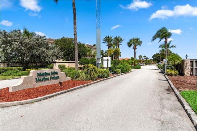 view of asphalt street featuring curbs, a gated entry, and a residential view