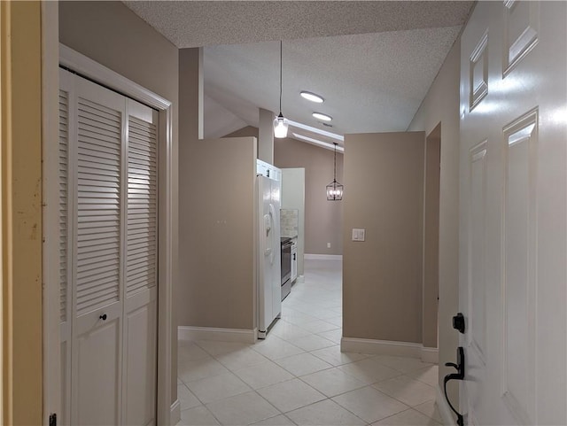 corridor with light tile patterned flooring, a textured ceiling, baseboards, and vaulted ceiling