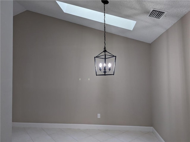 spare room featuring a textured ceiling, baseboards, visible vents, lofted ceiling with skylight, and an inviting chandelier